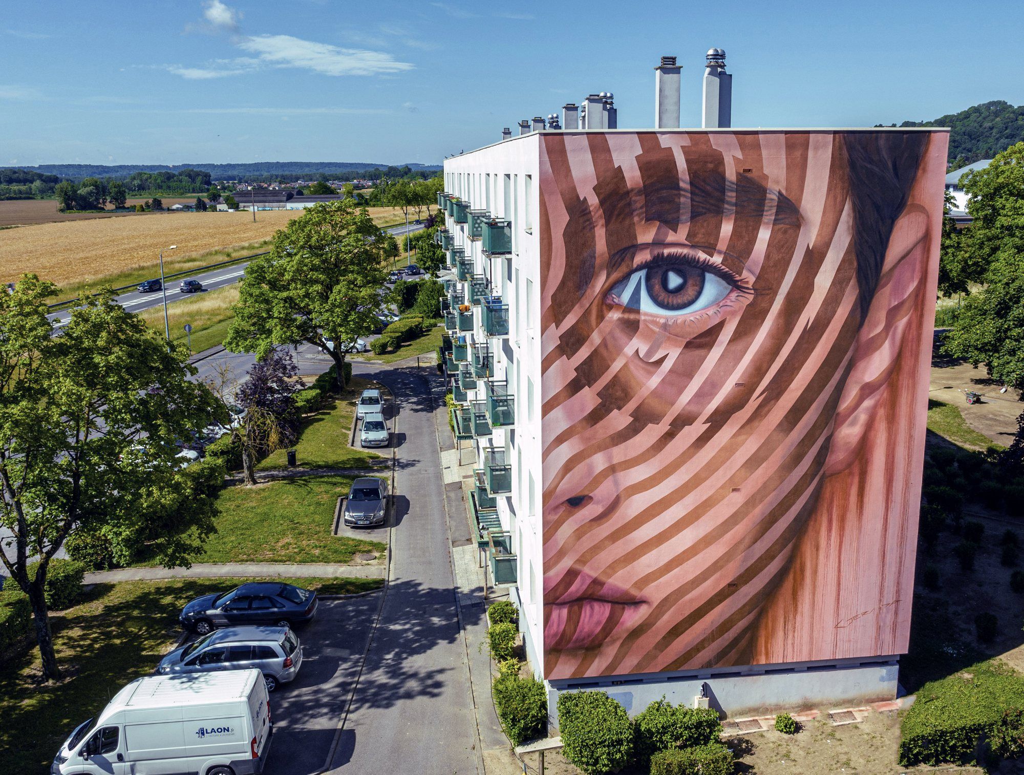Outsight, a painted portrait mural on a residential building in Laon, France